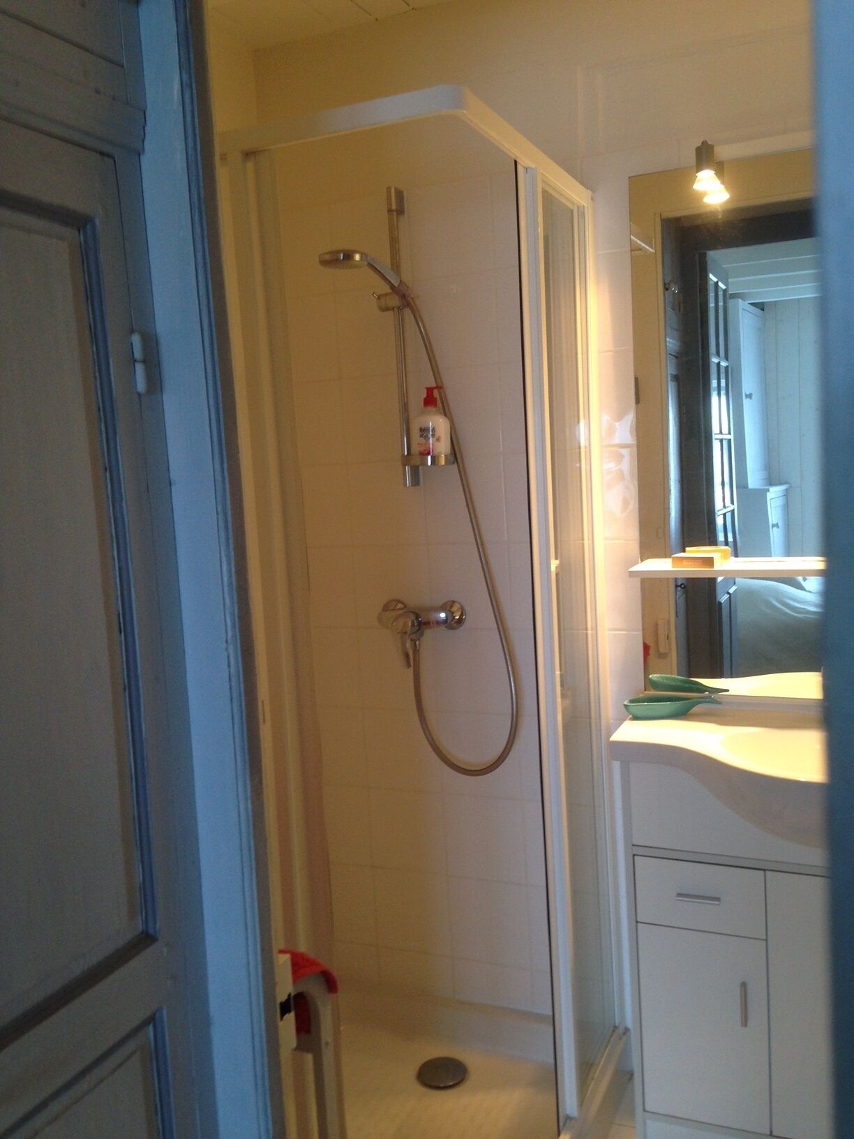 A bathroom with a shower, a sink, and a mirror.