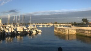 Un puerto deportivo con varias embarcaciones amarradas, un faro y un muro de piedra.