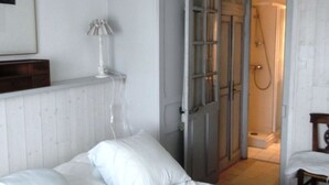 Un dormitorio con cama, lámpara y puerta que da a un baño.