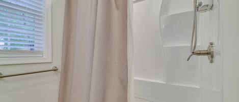 Un baño con ducha, toallero y retrete.