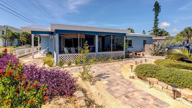 Une maison de plain-pied avec un porche couvert, une cour clôturée et une variété de plantes.