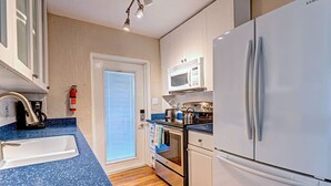 Une cuisine de taille réduite, équipée d’un réfrigérateur blanc, d’un four à micro-ondes, d’une cuisinière et d’un évier.