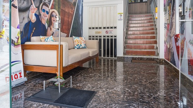 A hotel lobby with a sofa, a staircase, and a wall with a mural. - Hotel Tupinamba Neiva (Neiva)