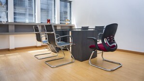 A modern office space with three black office chairs, a glass table, and a wooden floor. - Hotel Tupinamba Neiva (Neiva)