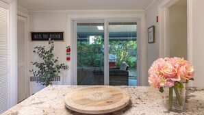A kitchen with a marble countertop, a wooden cutting board, a potted plant, and a vase of flowers. - Steps to Restaurants, Shops & Waterfront, Bar Island, Free 2-car Parking,  Wi-fi (Bar Harbor)