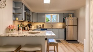 A modern kitchen with a central island, bar stools, a stainless steel refrigerator, and a skylight above the sink. - Steps to Restaurants, Shops & Waterfront, Bar Island, Free 2-car Parking,  Wi-fi (Bar Harbor)