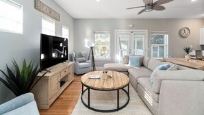 A modern living room with a television, sofa, coffee table, and ceiling fan.