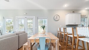 A modern kitchen with white cabinets, a wooden dining table, and blue chairs.