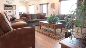 Un salon avec un canapé marron, un canapé gris, une table basse en bois et une plante en pot.