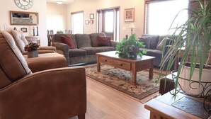 A living room with two sofas, a coffee table, and a clock on the wall. - Greystone Crossing Suite #8 (Heyburn)