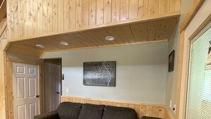 Un intérieur en bois avec un canapé, une porte et une œuvre d’art accrochée au mur.