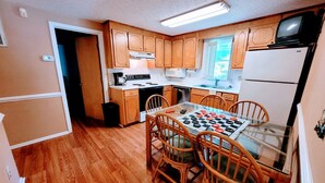 A compact kitchen with wooden cabinets, a microwave, a stove, and a refrigerator. - Sunsplash 5, walk to beach, walk to Main Street (North Myrtle Beach)