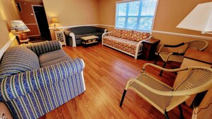 A living room with a sofa, two armchairs, a small table, and a window with blinds. - Sunsplash 5, walk to beach, walk to Main Street (North Myrtle Beach)
