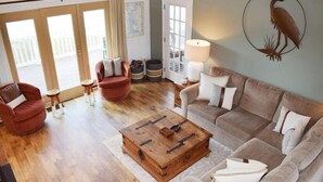 Un salón espacioso con una mesa de centro de madera, un sillón rojo, un sofá beige y una escultura de pájaro montada en la pared.