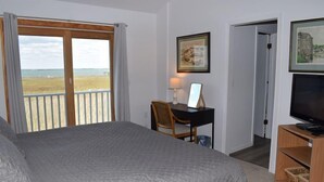Un dormitorio con una cama grande, un escritorio con silla, un televisor y un cuadro en la pared.