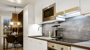 A modern kitchen with a built-in oven, a microwave, and a coffee machine.