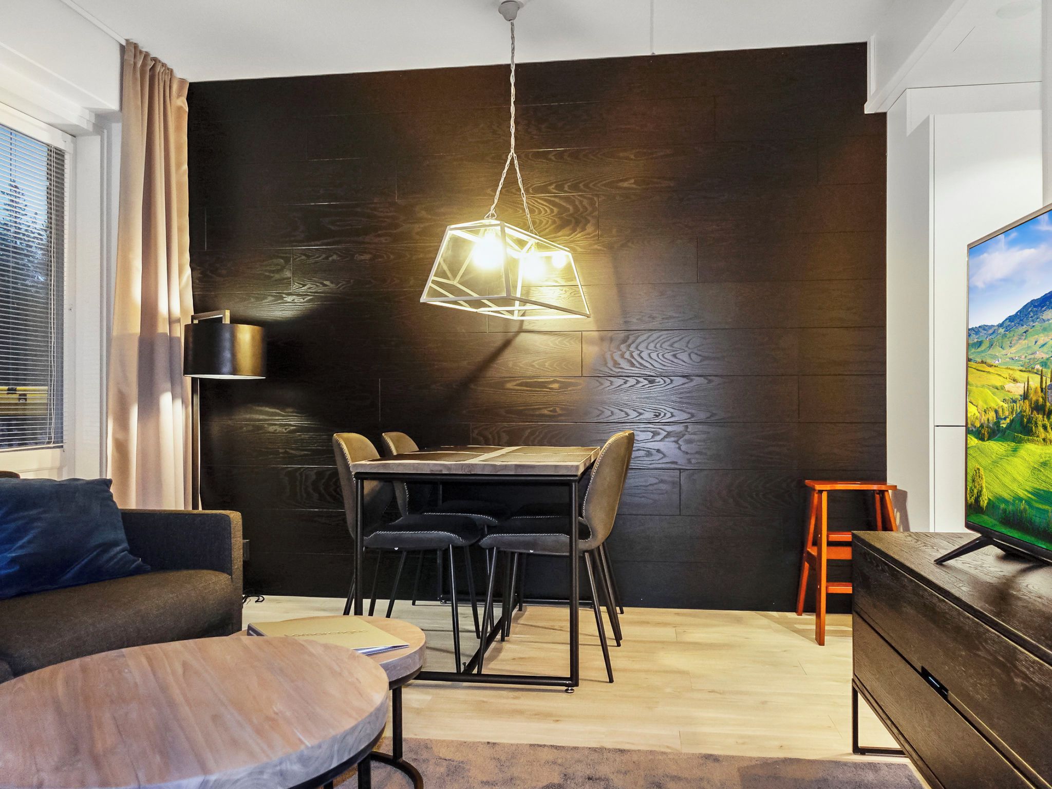 A modern living room with a dining area, a sofa, a TV, and a wooden wall.