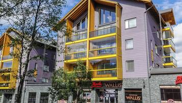 A multi-story building with a yellow and purple facade, featuring a restaurant named 'Hook Restaurant' and a karaoke bar named 'Wallis' Karaoke Bar'.