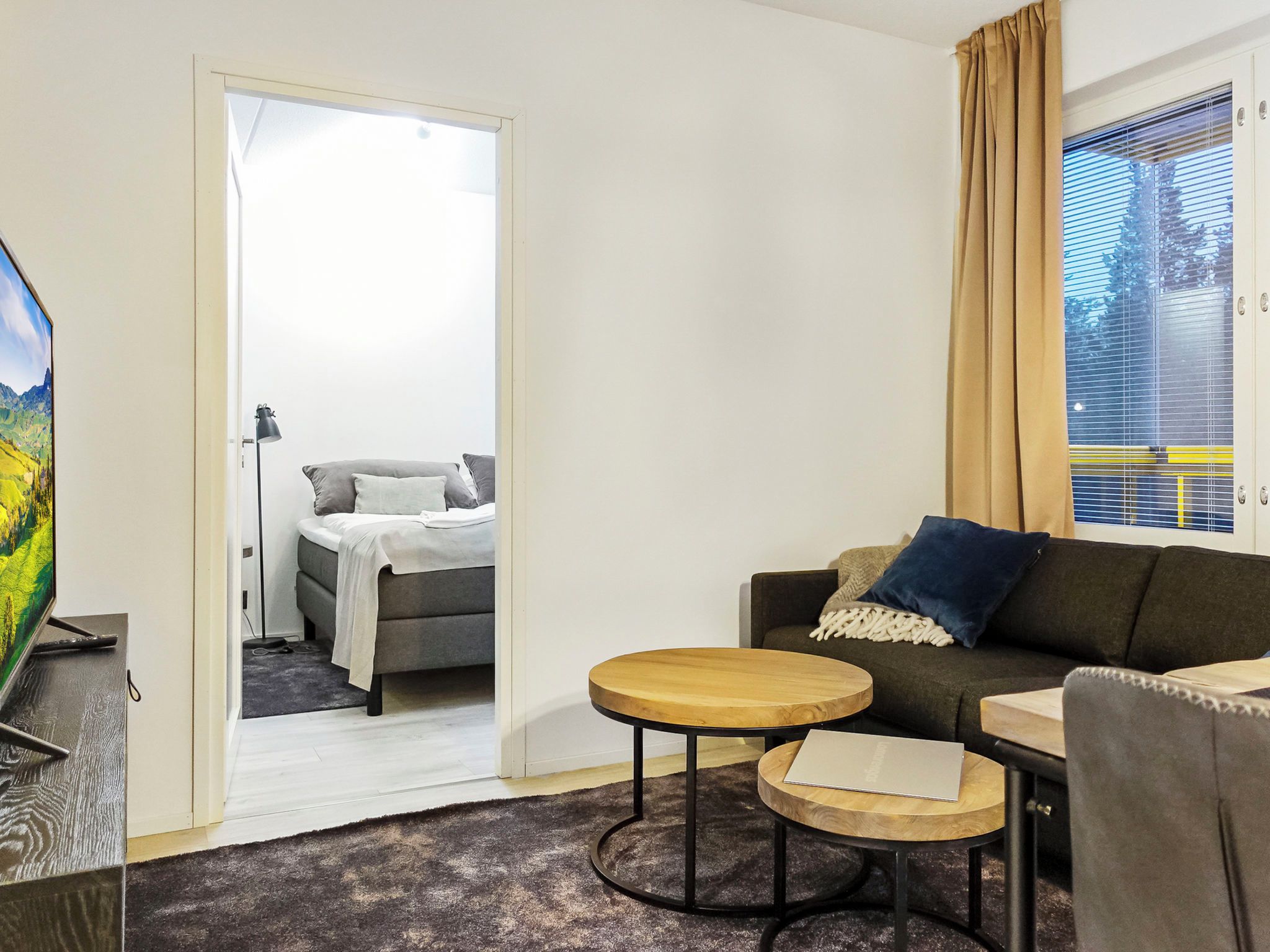 Una camera d'albergo con un letto, una poltrona, un tavolino e una televisione.