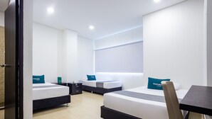 A hotel room with two beds, a desk, and a chair.