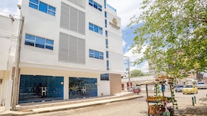 A white building with a sign reading "TRIPOLAD HOTEL" and a storefront with glass doors.