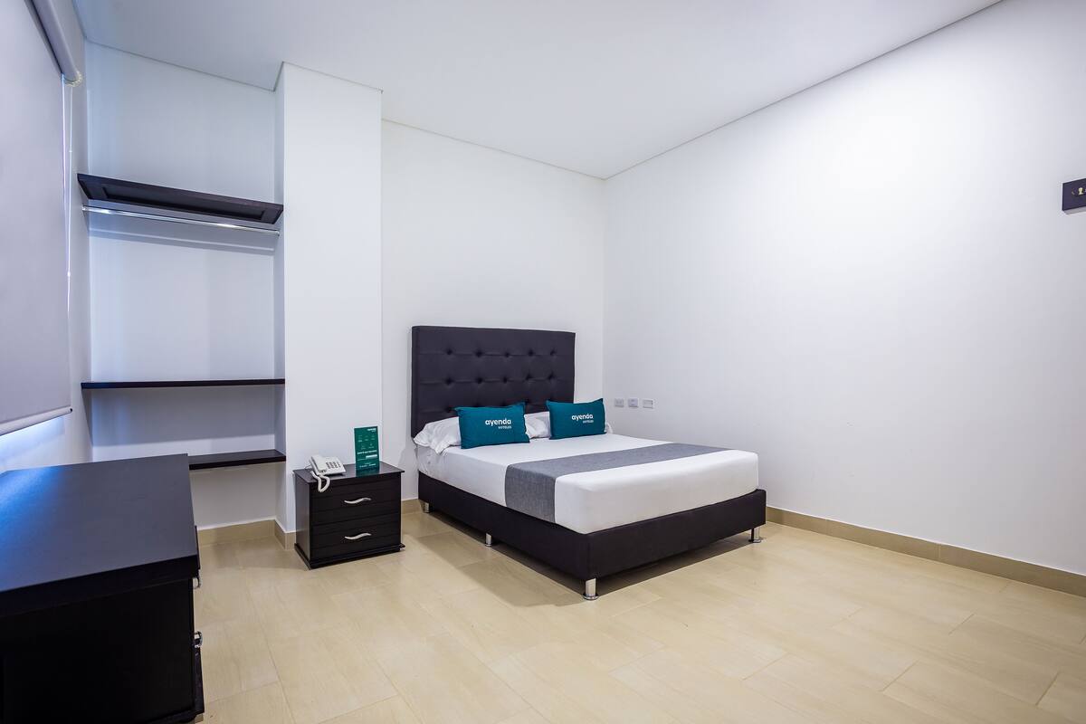 Ein modernes Schlafzimmer mit Bett, Nachttisch, Schreibtisch und Kleiderschrank.