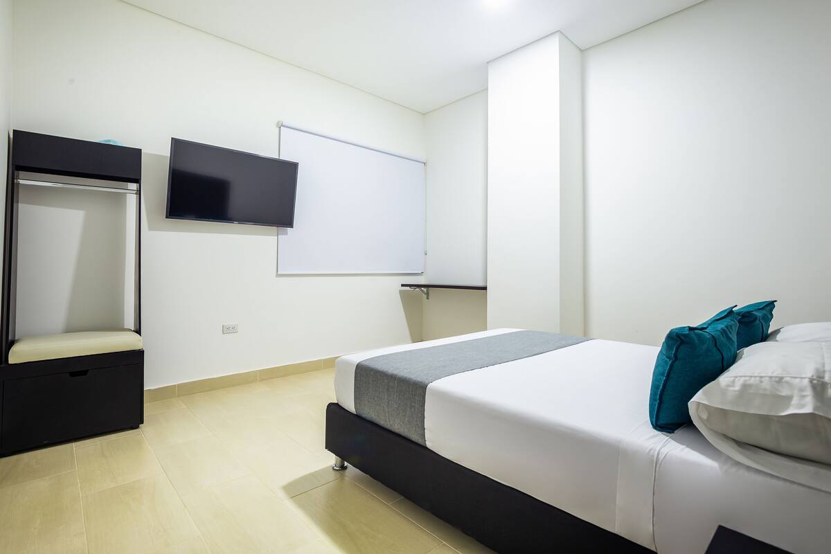 Ein Schlafzimmer mit einem Bett, einem Fernseher, einem Kleiderschrank und einer Whiteboard-Tafel.