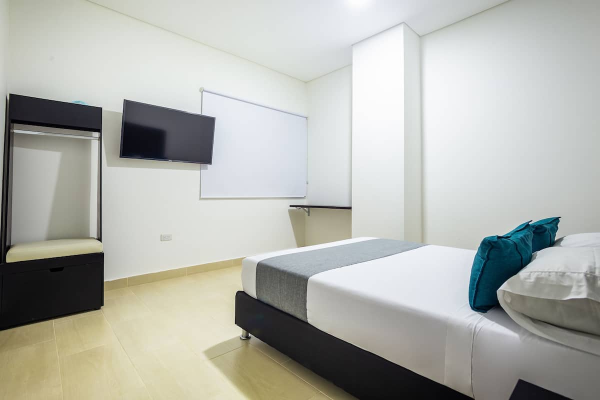 Une chambre à coucher comprenant un lit, un téléviseur, une armoire et un tableau blanc.