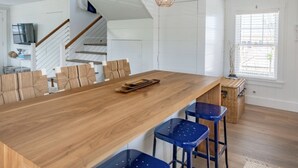 Una cuina moderna amb una illa de fusta, tamborets d'esbarjo i una escala que condueix a un altre nivell.