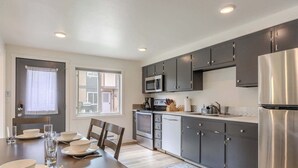 A modern kitchen with dark cabinets, stainless steel appliances, and a dining area with a table set for four.