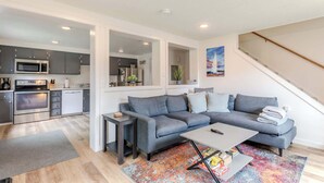 A modern living room with a grey sectional sofa, a coffee table, and a colorful rug.