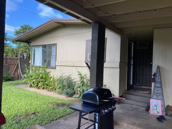 A house with a covered porch, a barbecue grill, and a welcome mat.