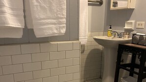 Um banheiro com azulejos brancos tipo metrô, piso com padrão hexagonal, pia, espelho e vaso sanitário.