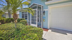 A house with a garage, a covered entryway, and a palm tree. - Modern Beach Retreat w/ Pool, Hot Tub, & Patio! (Fort Myers)