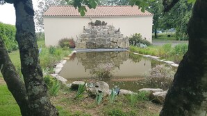 Ein Garten mit Teich, Steintreppe und einem Gebäude mit Ziegeldach.