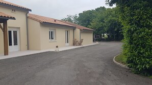 Ein Gebäude mit einem Ziegeldach, einer Schotterauffahrt und einer kleinen Sitzecke mit zwei Stühlen und einem Tisch.