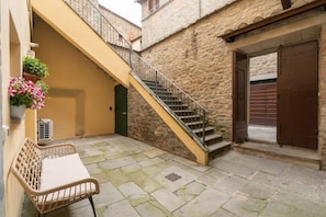 A stone building with a staircase leading to an upper level, a bench, and a door.