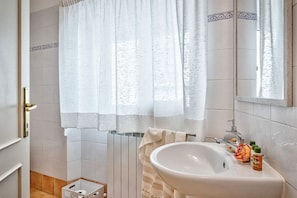 Ein Badezimmer mit einem weißen Waschbecken, einem Handtuchhalter und einer Duschvorhang.