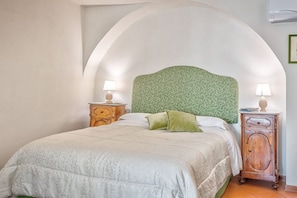 A bedroom with a large bed, two bedside tables, and an arched ceiling.
