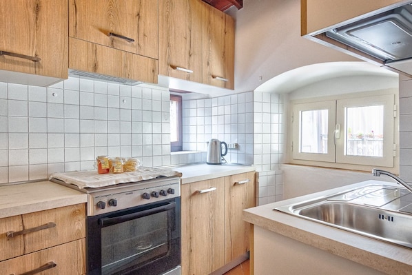 A kitchen with wooden cabinets, a stove, a sink, and a window.