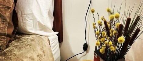 A bedroom with a bed, a bedside table with a book and a vase of yellow flowers.