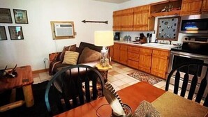 A dining area with a table, chairs, a lamp, and a decorative bird. - The Hideaway at Bear Mountain Log Cabins (Eureka Springs)