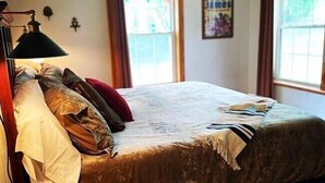 A bed with a brown bedspread, a white pillow, and a red pillow. There is a lamp on the left side of the bed. - The Hideaway at Bear Mountain Log Cabins (Eureka Springs)