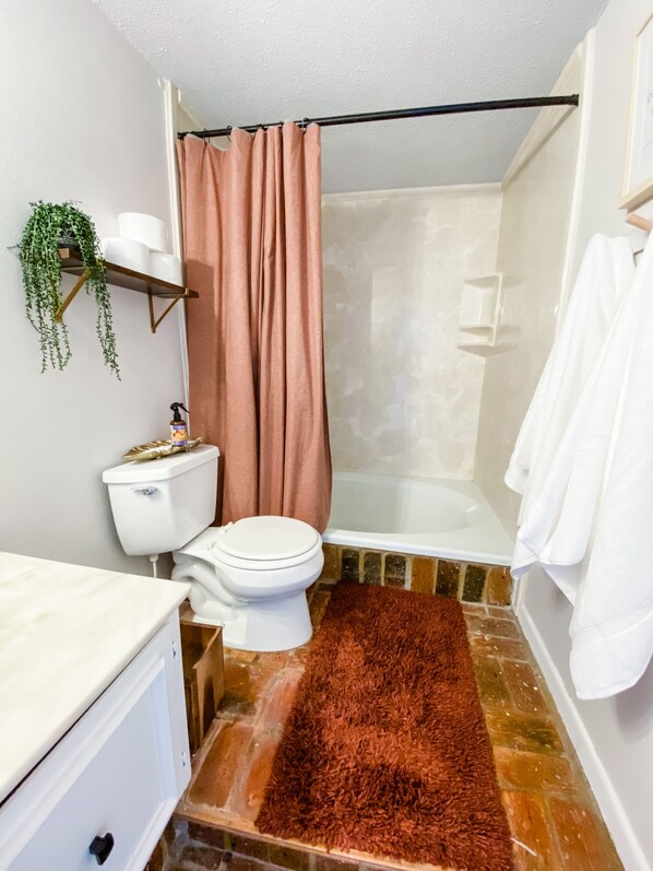 A bathroom with a toilet, shower, and a brown rug. - Warm and Cozy Condo with Peaceful Golf Course Views (Daphne)