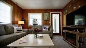 Una sala de estar acogedora con un sofá, una mesa de centro con un libro, un televisor y una chimenea.