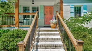 A wooden staircase leading to a porch with a red door, a potted plant, and a small table with chairs. - Bright & Cheery Bungalow - Mins to Downtwn Fort Mill (Fort Mill)