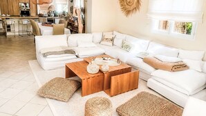 Ein modernes Wohnzimmer mit einem Ecksofa, einem Holztisch und gewebten Poufs.