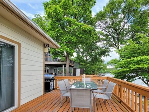 A deck with a table and chairs, a grill, and a view of a body of water.