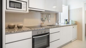 Een moderne keuken met witte kasten, een ingebouwde magnetron, een fornuis en een spoelbak.