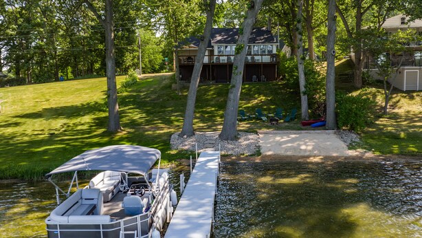 Een boot ligt aangemeerd aan een steiger, met een huis op de achtergrond.
